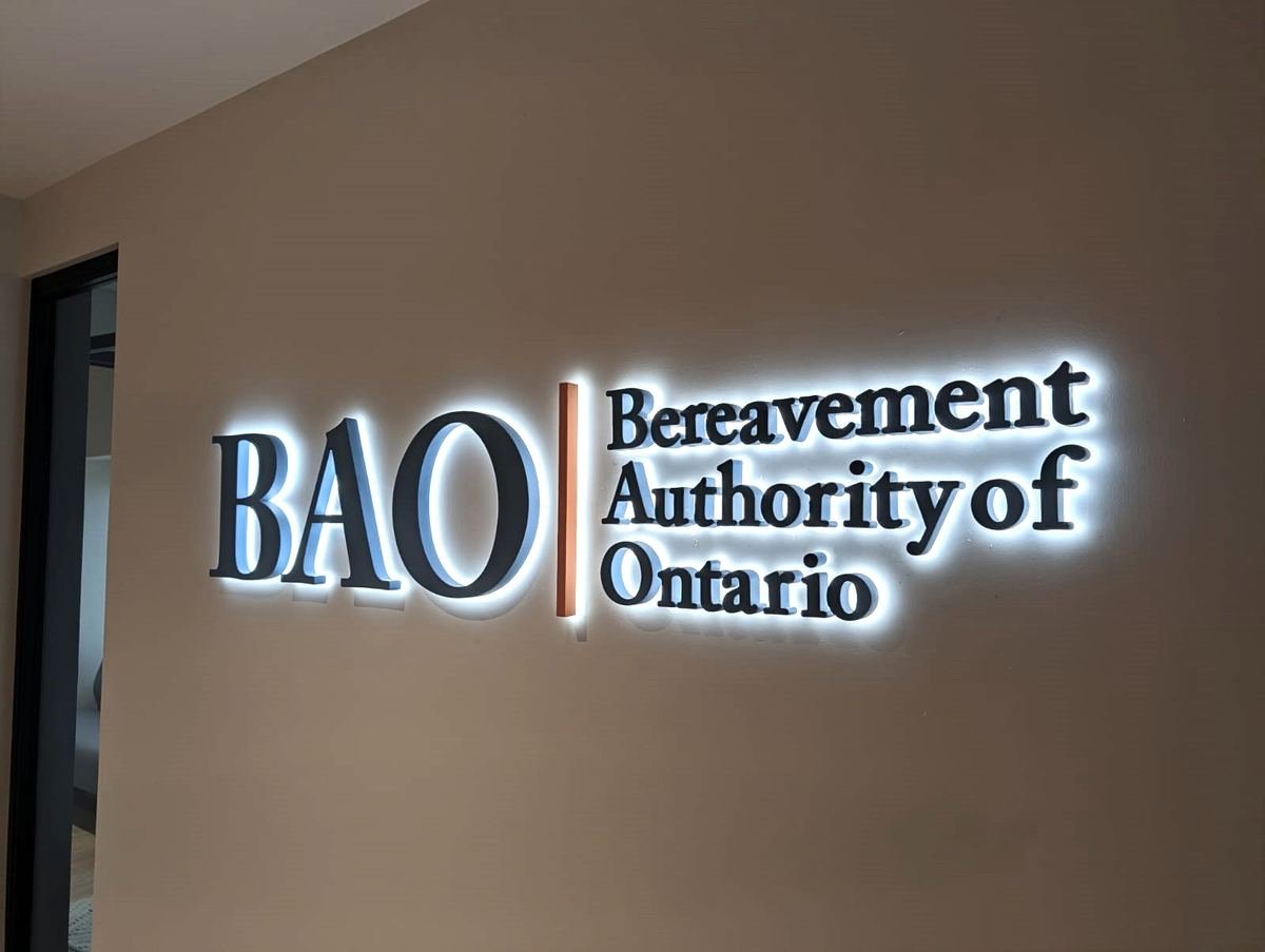 Dark BAO and Bereavement Authority of Ontario letters with a white halo glow on a taupe wall