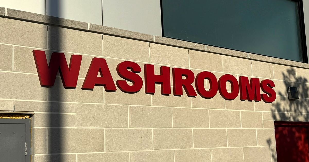 Red cut-out letters spelling Washrooms on concrete masonry wall