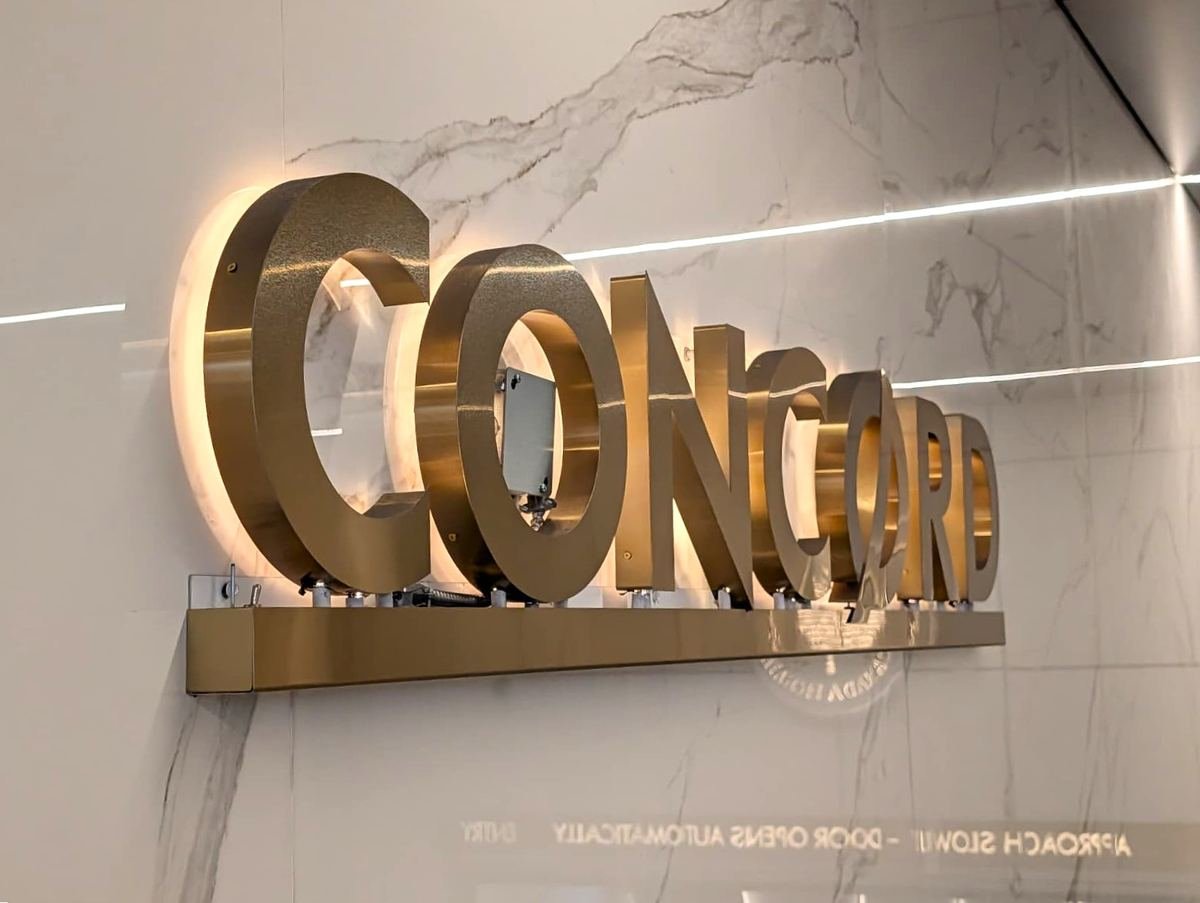 Gold CONCORD letters with a warm halo glow on a white marble wall