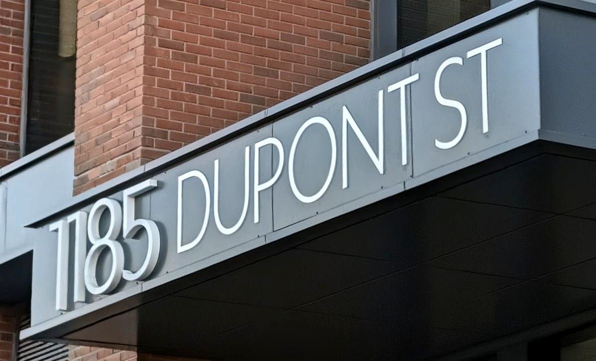 White dimensional address letters reading 1185 DUPONT ST mounted to an entrance canopy