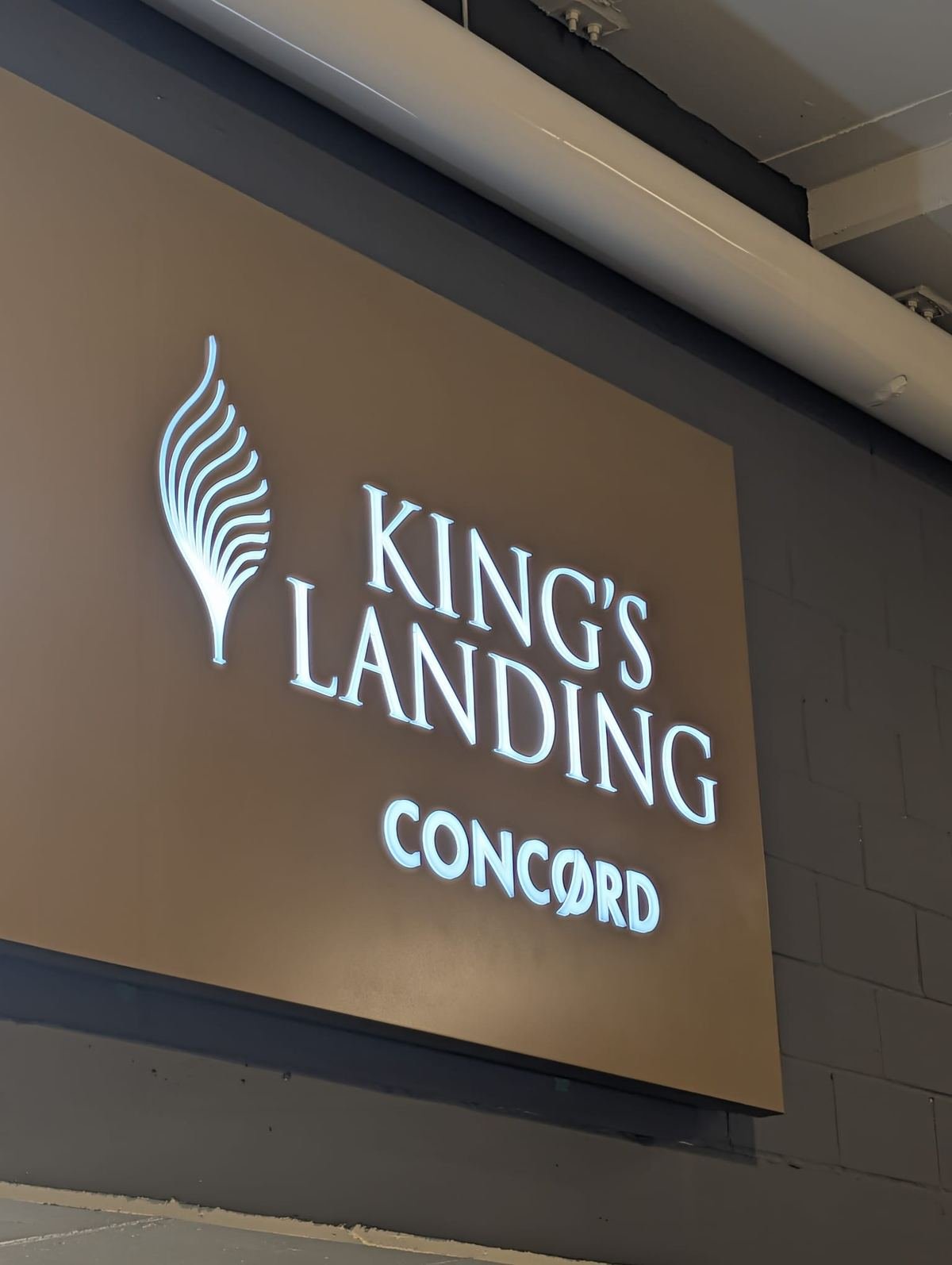 Glowing white King's Landing lettering, leaf logo and CONCORD on a bronze-toned panel